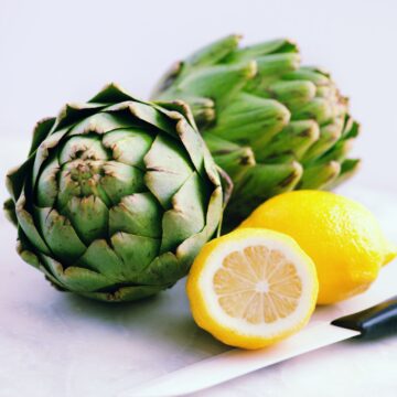 High protein artichokes with lemon slices and a knife.