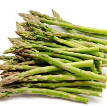 A pile of green asparagus, a high protein low carb vegetable, on a white background.