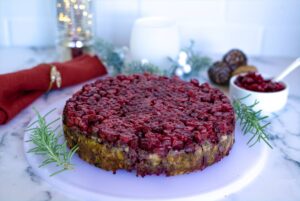 Nut roast with cranberries on top on a white plate.