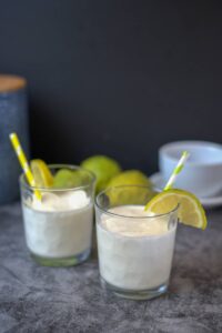 two glasses with a lemon smoothie and slices of lemon on the rim