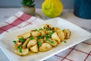 Roasted potatoes and baby turnips with parsley on a white plate.