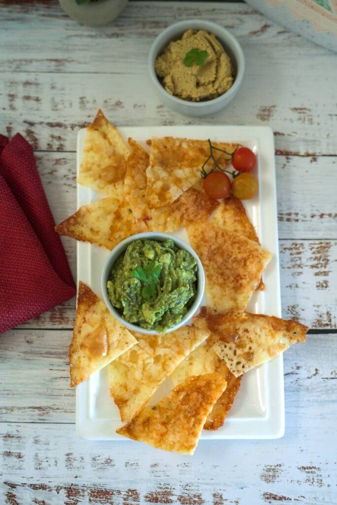 cheese chips cut into nacho shapes with an avocado dip
