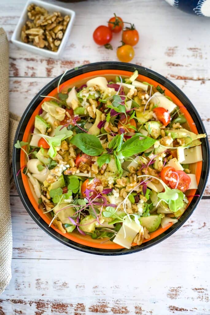 palm hearts, avocado, tomato and walnut salad in a serving bowl.