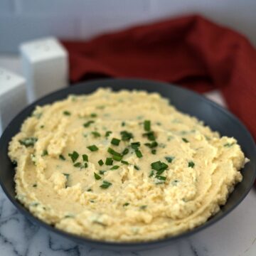 A bowl of low carb mashed potatoes with chives.