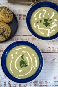 Two bowls of soup with sour cream and chives, topped with broccoli.