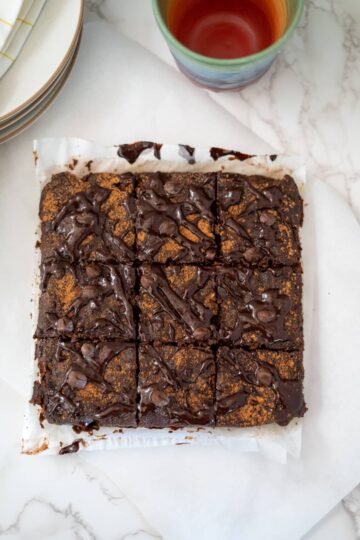 Tahini brownies on a plate with a cup of tea.