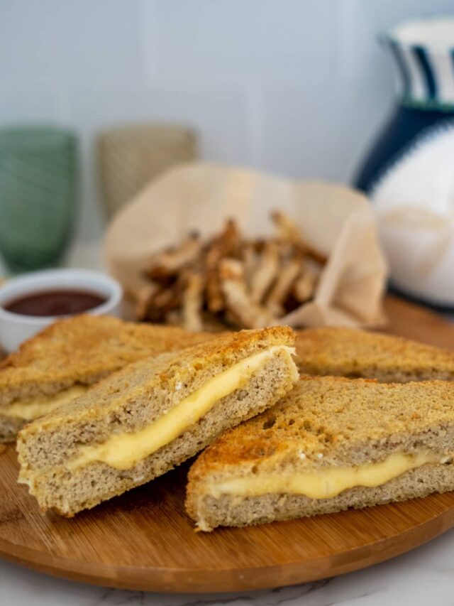 grilled cheese sandwiches on a wooden tray with fries in the background