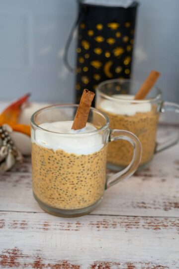 Keto chia seed pudding in mugs with cinnamon sticks.
