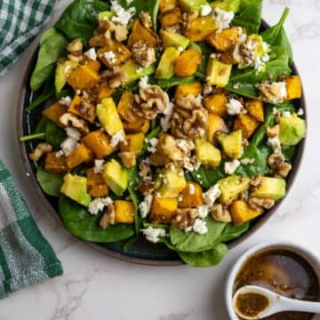 Pumpkin chunks on a bed of spinach with feta cheese, avocado and walnuts.