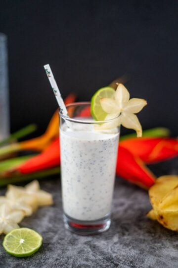 A glass of coconut milk smoothie with pineapples and limes.