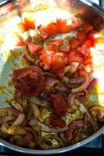 tomatoes, spices and onions in a large pan