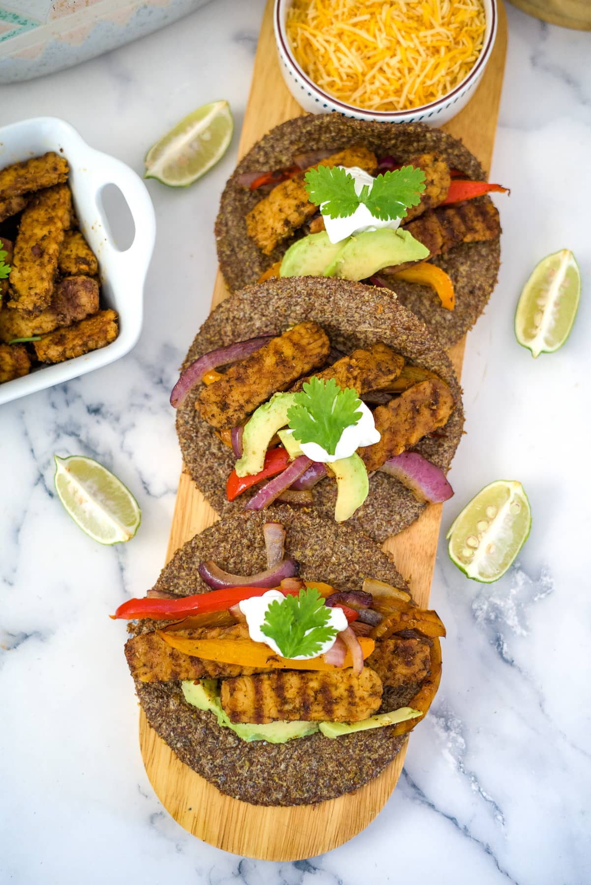 tempeh fajitas on a wooden board in tortillas