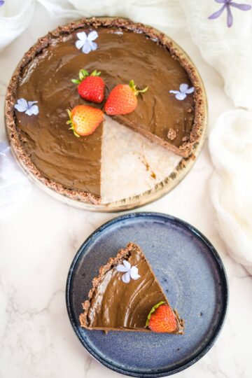 A no bake chocolate tart with strawberries on a plate.