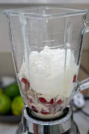A blender filled with cottage cheese smoothie and strawberries.