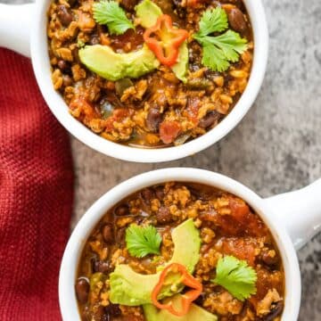 Two bowls of TVP chili with avocado and tomatoes.