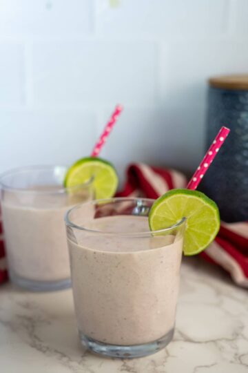 Two glasses of cottage cheese smoothie with a lime slice on top.