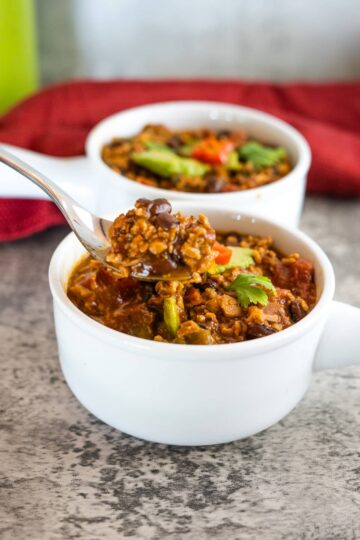 A spoonful of chili from a white bowl