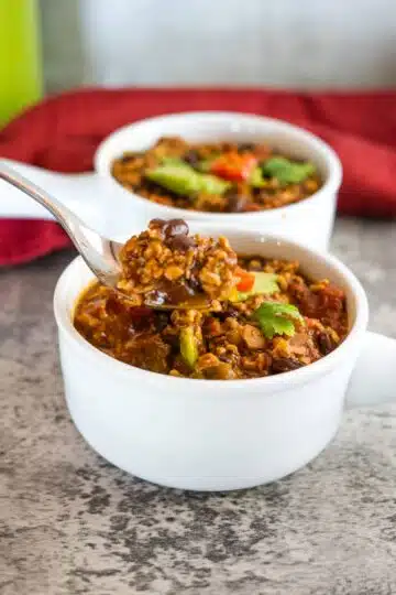 A spoonful of chili from a white bowl