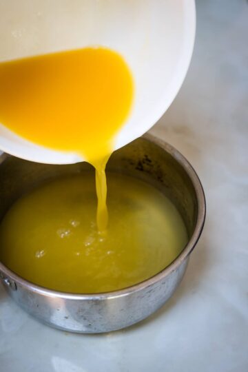 An egg is being poured into a bowl of liquid.