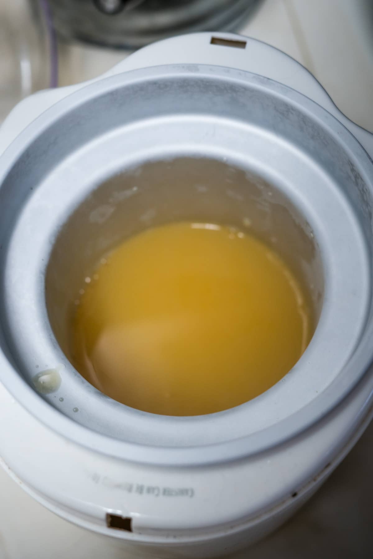 A bowl of yellow liquid sitting on a counter.