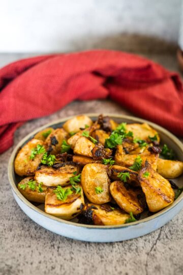 Roasted potatoes on a plate with a red cloth, accompanied by fried turnips.
