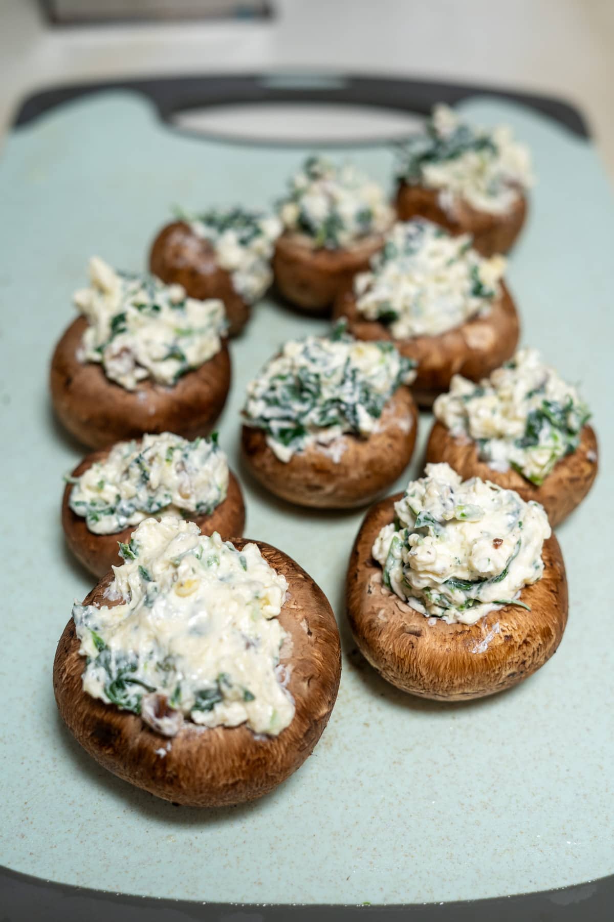 Air fryer stuffed mushrooms with spinach and cheese on a cutting board.