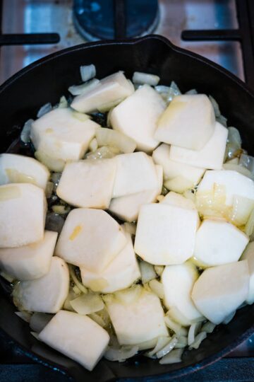 Fried turnips in a skillet on a stove.