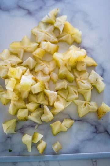 Chopped pineapple on a cutting board, ready for star fruit jam.