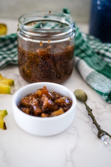 A jar of star fruit jam with a spoon next to it.