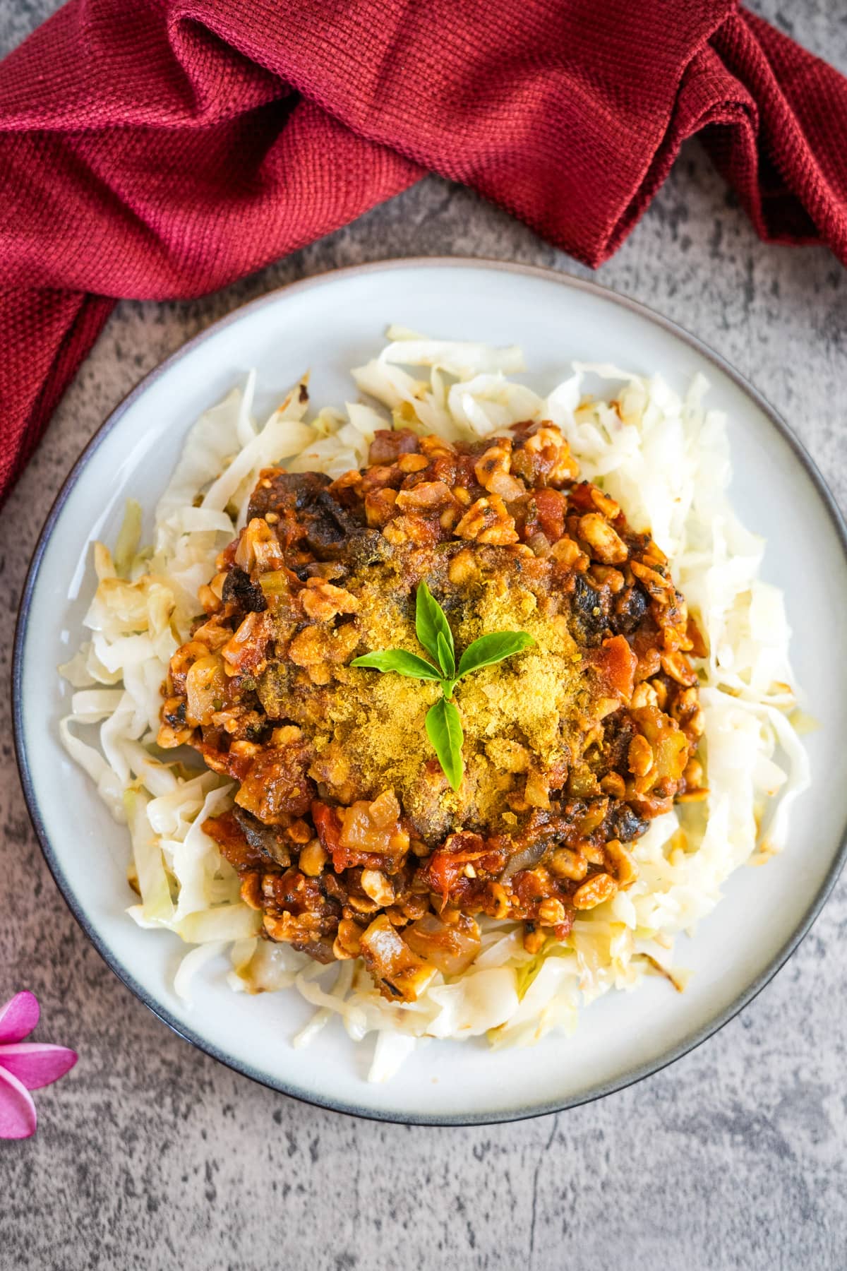 A plate of curry on a table with a flower on it.