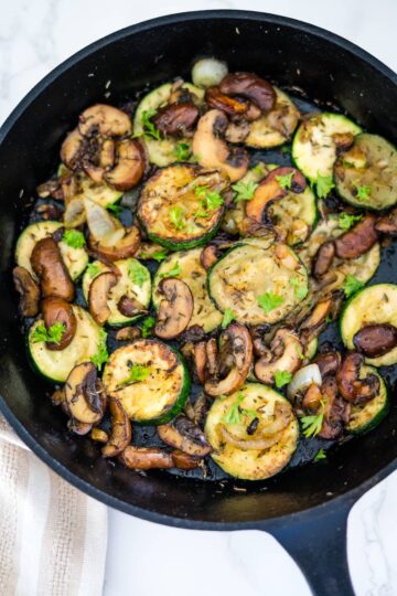 Zucchini and mushrooms cooked in a skillet.