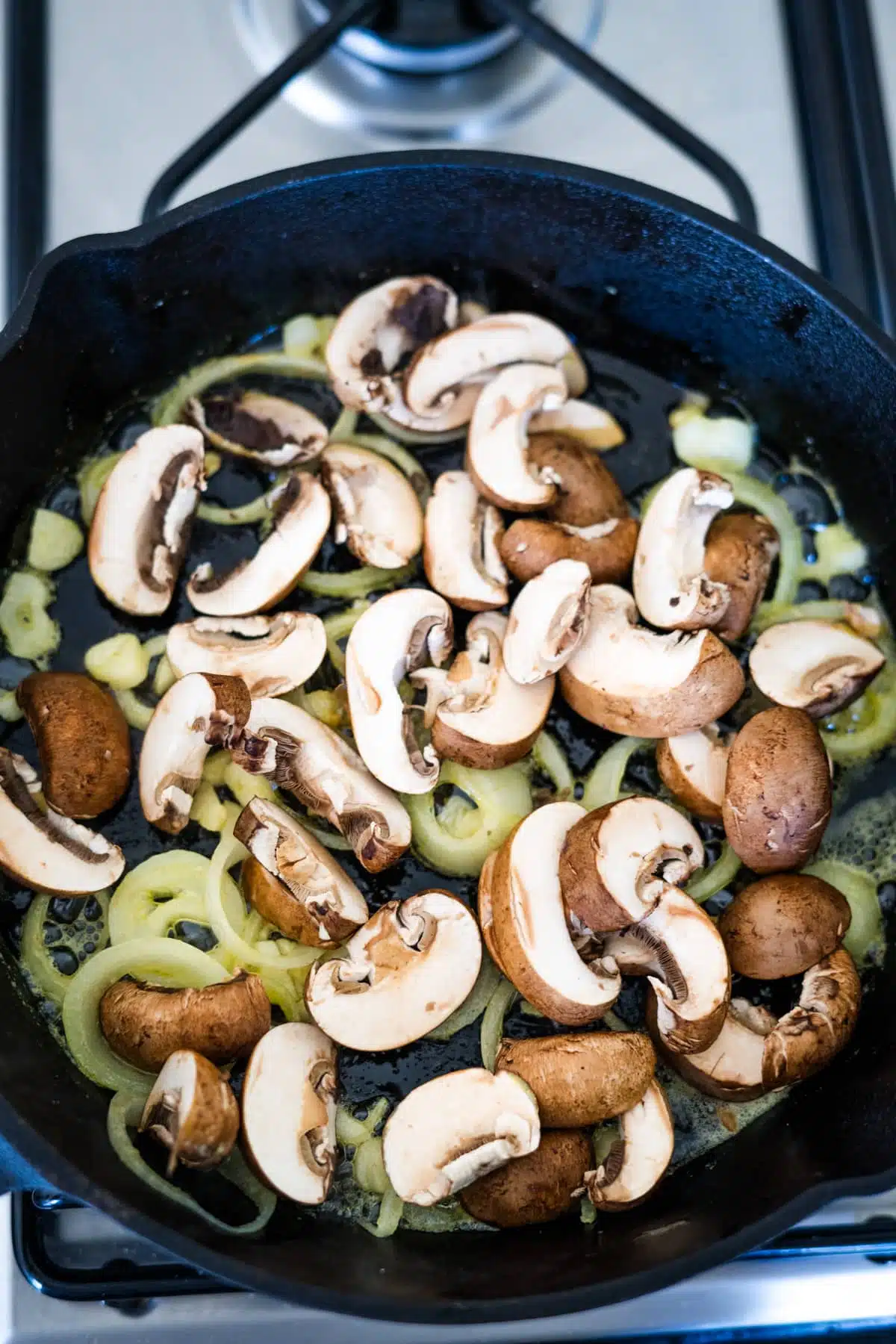 A skillet filled with mushrooms and zucchini on a stove.