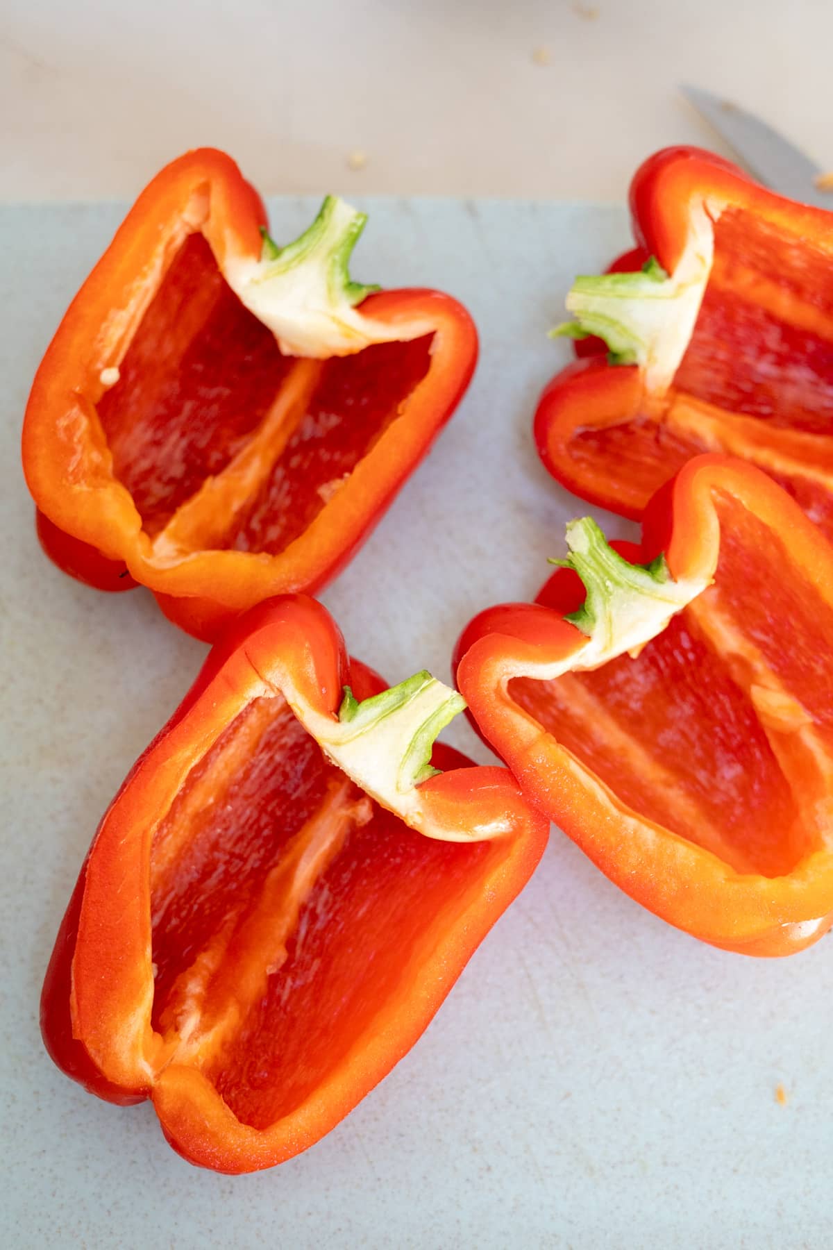 Four red peppers cut in half on a cutting board.