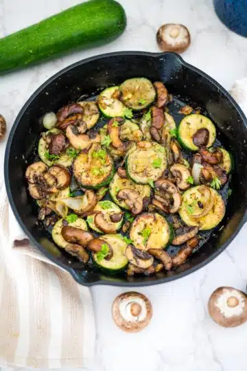 A skillet filled with zucchini and mushrooms.