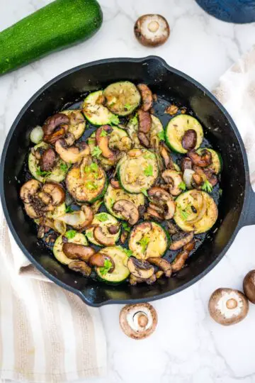 Sautéed zucchini and mushrooms in a cast iron skillet.