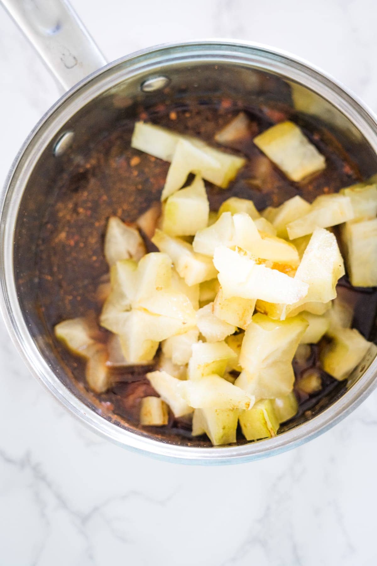 A pan with sliced apples and onions, cooked in star fruit jam.