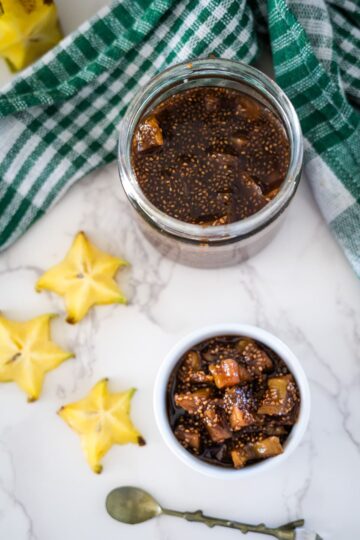 A jar of star fruit jam and a spoon next to it.