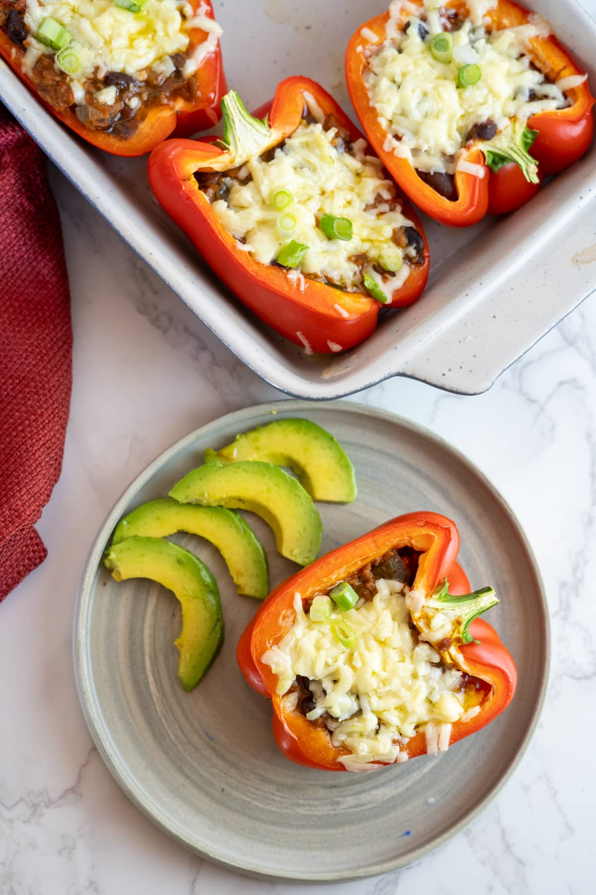 Stuffed peppers with cheese and avocado on a plate.