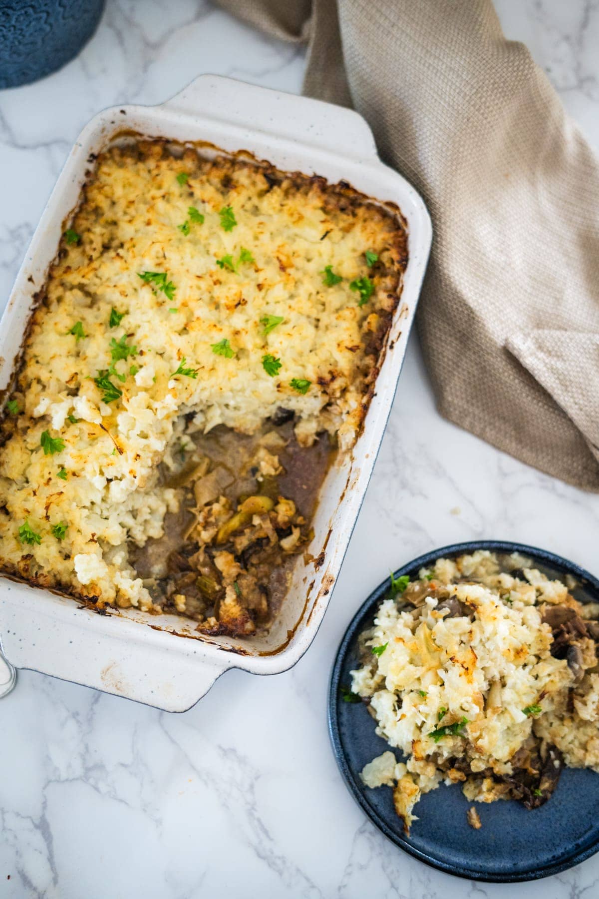 A mushroom and leek cottage pie served with a bowl of mashed potatoes.