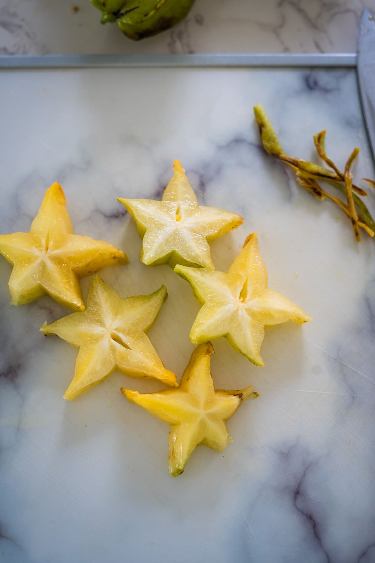 Sliced star fruit on a cutting board with a knife, perfect for making star fruit chutney.