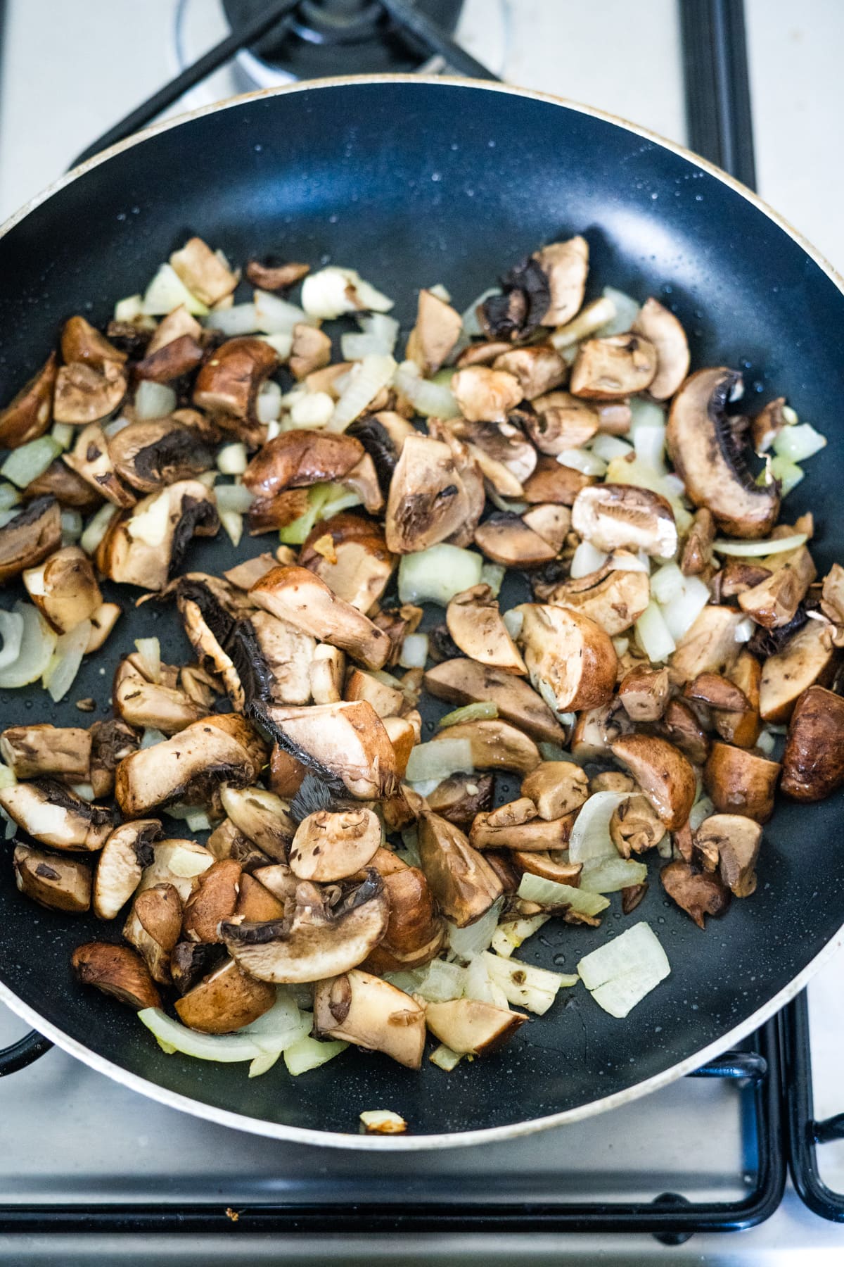 A frying pan with mushrooms and onions on it, cooked to perfection using an air fryer.