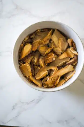 Sliced mushrooms in a bowl on a marble counter, perfect for mushroom tofu soup.