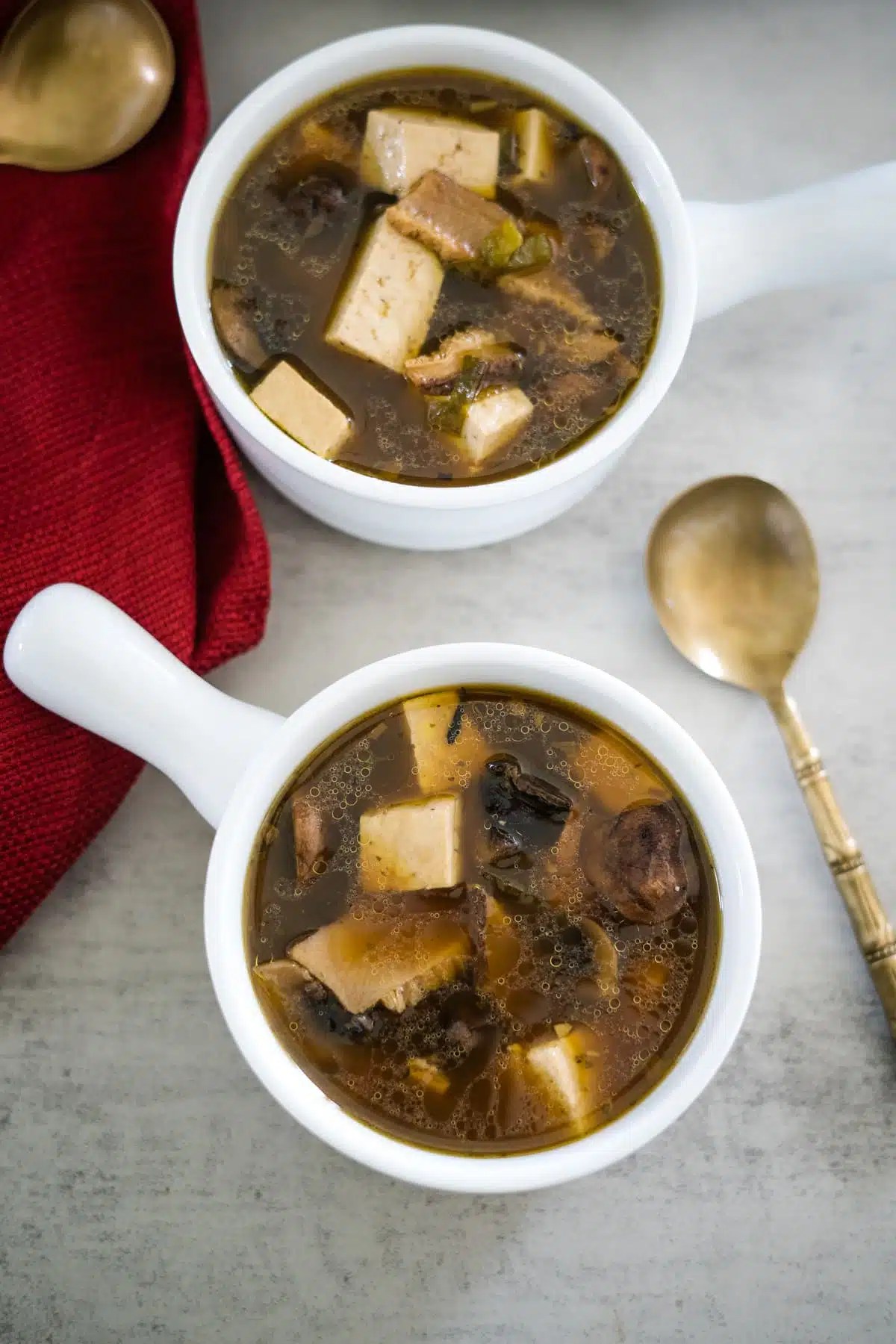Two bowls of soup with tofu and mushrooms.