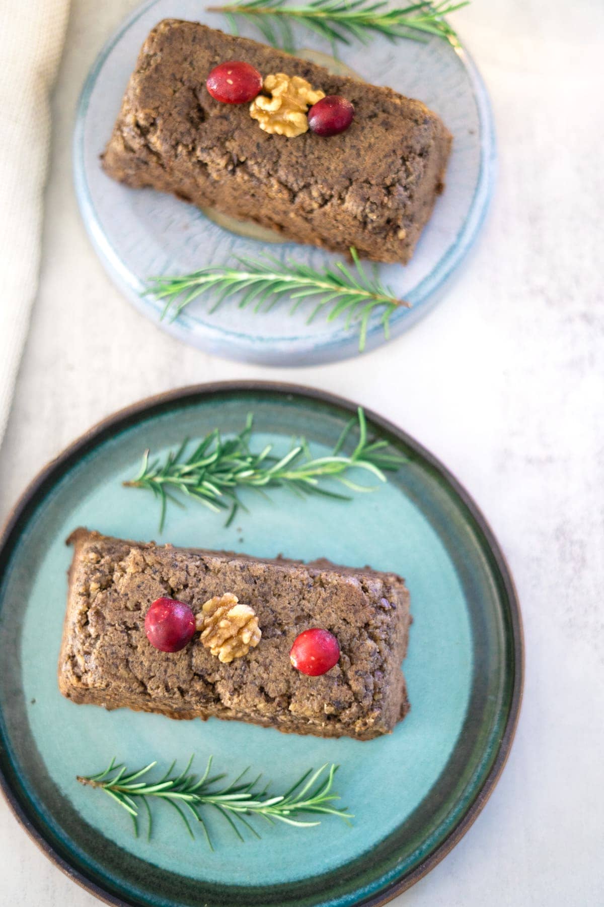 Two plates of cranberries and sprigs of rosemary served alongside an air fryer nut roast.