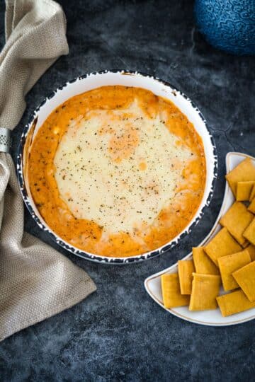 A bowl of dip with crackers next to it, showcasing a delightful combination of cottage cheese and crackers.