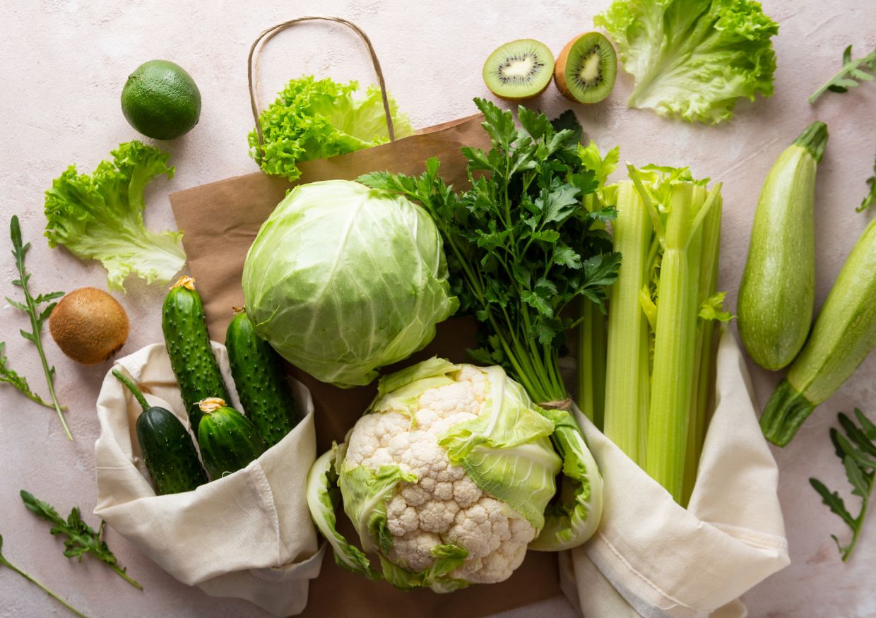 Fresh vegetables in a paper bag on a white background.