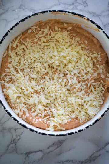 A bowl of cheesy brownies on a marble countertop, featuring a savory twist with the addition of cottage cheese.