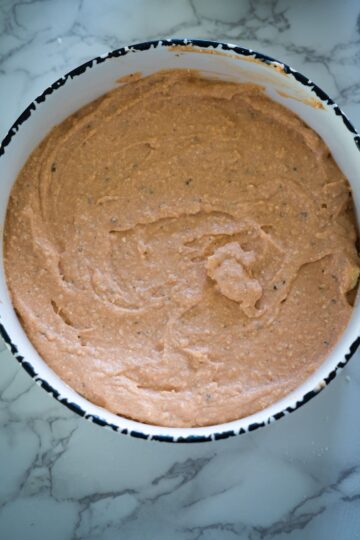 A bowl filled with a brown batter, resembling a pizza crust.