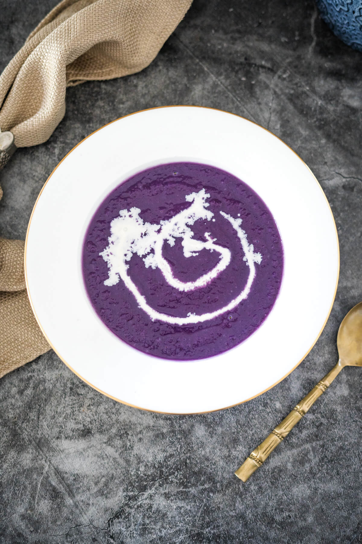 A bowl of red cabbage soup on a table with a spoon.