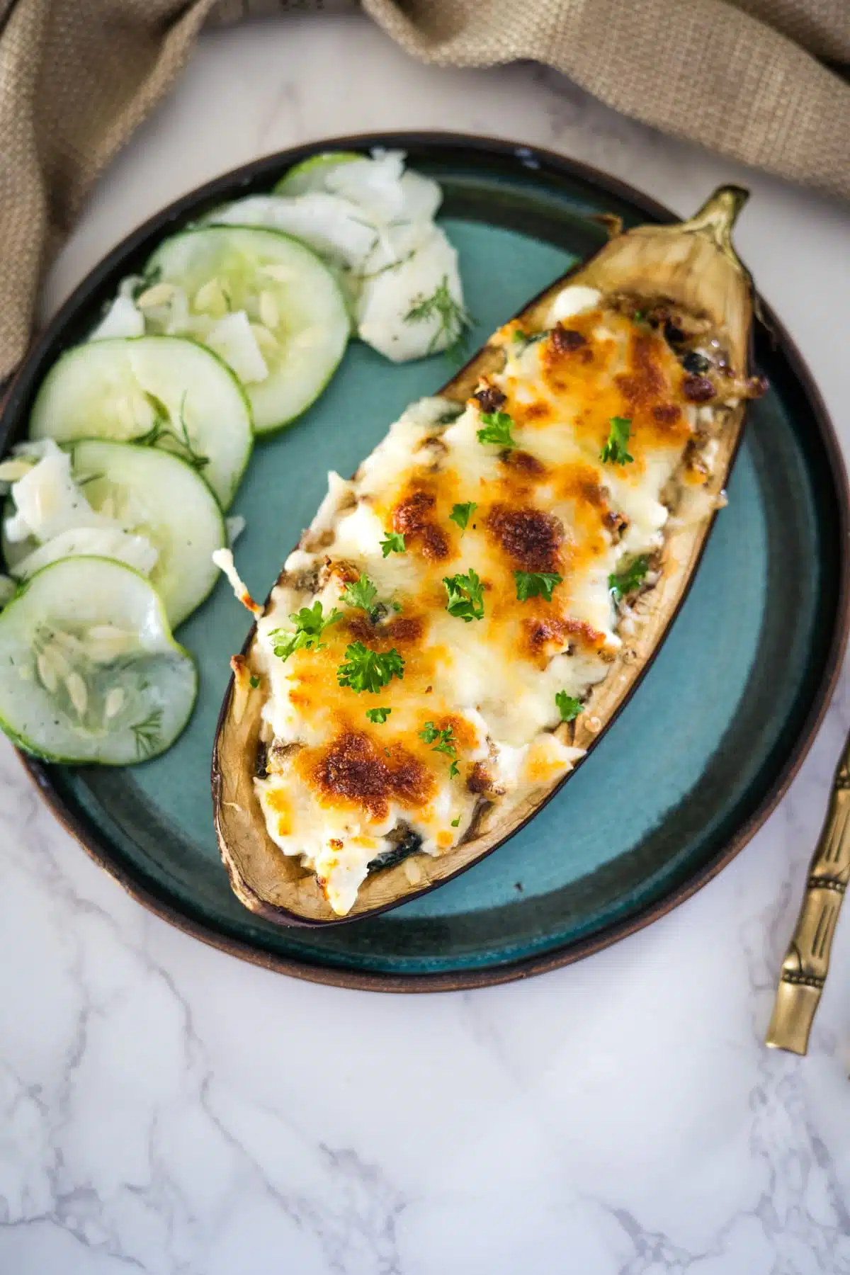 Stuffed eggplant with feta cheese and cucumbers on a plate.